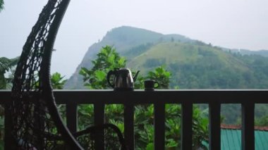 Dağ manzaralı sabah içkisi, lüks bir verandaya sandalye asmak, sakin bir çiftlik manzarası rahatlamaya davetiye çıkarır. Ella Kayası 'na bakan balkonda metal çaydanlık ve fincan, Sri Lanka' da çay tarlaları. Yavaşla