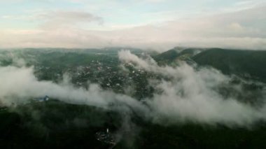 Sabahın erken saatlerinde renkler manzaraları yıkıyor. Gün doğumunda Nuwara Eliya üzerinde insansız hava aracı uçuşu, sisli dağlar, uyanış kasabası. Sri Lanka güzelliğinde, sakin dağların üzerinde gün ışığı parıldıyor..