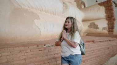Sırt çantalı kıdemli Asyalı kadın antik dağ mağarasını keşfediyor, namaste 'de uyuyan Buda heykelini selamlıyor, yıpranmış taş dokularına dokunuyor, kültür, tarih ve maneviyata etkin hale geliyor. Slomo