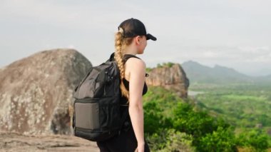 Solo gezgin manzaraları fotoğraflıyor, Sri Lanka manzarasını keşfediyor, seyahat anılarını kaydediyor. Maceraperest bir kadın sırt çantasıyla dağdan aşağı iniyor ve Sigirya Kaya Panoramasını akıllı telefonuyla yakalıyor. Slomo