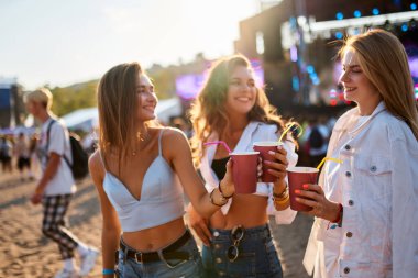 İçki içiyorlar, gülüyorlar, gün batımında dans ediyorlar. Bir grup kız kumsalda yaz müzik festivalinin tadını çıkarıyor. Sahneli parti atmosferi, arka planda kalabalık. Sıradan moda, kaygısız gençlik havası..