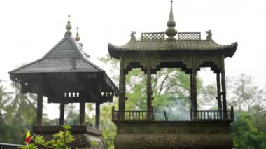 Ambiyans yağmurunda bukleler tütüyor, bağlılığı iletiyor. Tütsü, Budist tapınağında tütsülenir. Antik mimari, dingin sahnede meditasyon fitili. Zamane ritüelleri ve farkındalığı.