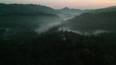 Yeşil tepeler, uyanık kuşlar, sakin doğada yuva yapmış tenha evler. Ella dağlarının üzerinden geçen insansız hava aracı sisli şafak, Sri Lanka. Rahatlama ve eko-turizm temaları için mükemmel bir zemin.
