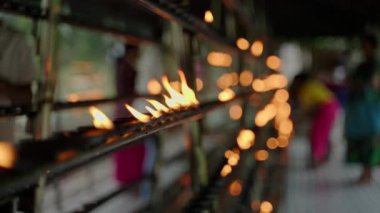 Alevler yanıp sönüyor, sakin bir ortam yaratıyor. Budist ayinlerinde gaz lambaları yakar. Renkli giysiler içinde ibadet edenler dini uygulamalar yaparlar, dua ederler. Kültürel tören, gelenek ruhsal mekan. Yavaşla