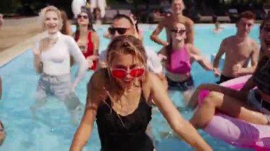 Erkek arkadaşlar ve kız arkadaşlar lüks kulüpteki havuz partisinde yaz havasının tadını çıkarıyorlar. Erkekler ve kadınlar gülümser, el sallar, dalarlar ve turkuaz berrak suda yüzerler. Arkadaşlarla sıcak tatilde gürültülü bir kutlama.