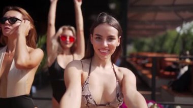 Yaz havuzu partisinde renkli bikiniler ve güneş gözlükleriyle poz veren, dans eden ve flört eden kadın ve erkekler. Arkadaşlar tatil için havuz ve dinlenme yerlerinde tatil yapıyorlar..