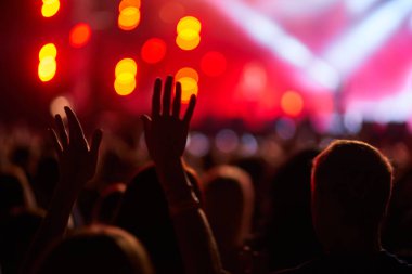 Enerjik kalabalık konser ve gece eğlencesinden hoşlanıyor. Hayranlar coşkulu açık hava müzik festivalinde heyecan içinde el kaldırıyor. Işıklar sahneyi aydınlatıyor, dinamik atmosfer. Heyecan açık olayı doldurur.
