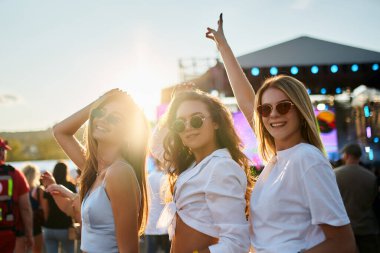 Kızlar dans eder, yaz havasında güler. Arkadaşlar plaj müzik festivalinde günbatımının tadını çıkarırlar. Grup, kıyı etkinliklerinde kalabalık ve parti atmosferiyle kutlama yapıyor. Açık hava konserindeki mutlu gençler eğleniyorlar..
