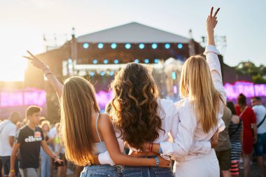 Arkadaşlar sarılır, kutlanır, kalabalık içinde dans eder, yaz partisi havası yaratır. Plaj müzik festivalindeki bir grup kız, kollarını kaldırıp günbatımının tadını çıkarıyorlar. Sahnede gün ışığı parlıyor, festivale katılanlar toplanıyor, açık hava eğlencesi..