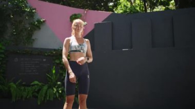 Formda bir kadın başarılı bir eğitim seansı, sağlık odaklı bir yaşam tarzı. Spor kıyafeti giymiş kızıl saçlı bayan sporcu açık hava tropik spor salonunda derin derin nefes alıyor, kendine güven egzersizden sonra yayılıyor. Yavaş çekim.