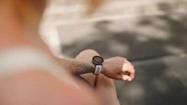 Profesyonel sporcu kadın kalp atışlarını, kalorileri, tropik ortamları izliyor. Kızıl saçlı sporcu spor salonundaki eğitimden sonra akıllı saati kontrol eder. Fitness seansı, güneş ışığında sağlık istatistikleri. Yavaşla