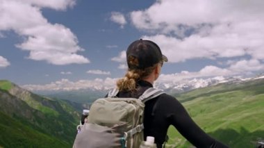 Sırt çantalı kadın yürüyüşçü dağları sever. Elinde yürüyüş direkleri var, Büyük Kafkasya 'daki Svaneti dağlarına hayran. Manzaralı dağ manzarası, doğa yürüyüşü macerası. Yavaş çekim.