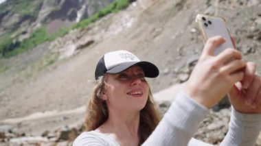 Yürüyüşçü kadın akıllı telefonuyla dağ manzarasının fotoğraflarını çekiyor. Dişi kaşif açık hava macerasını sever, manzarayı yakalar. Belgesel, yürüyüş, doğa aşığı fotoğrafları. Yavaş çekim.
