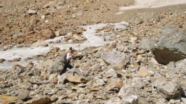 Maceracı kadın nehir boyunca kayalık dağ arazisinde yürüyüş yapıyor. Sırt çantalı yalnız gezgin. Açık hava öncülüğü, fiziksel meydan okuma doğa. Aktif yaşam tarzı dağ macerası. Yavaş çekim.