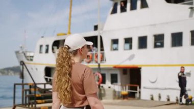 Günlük kıyafet, deniz kenarından zevk alıyor, rıhtımda gemiye yaklaşıyor. Güneşli bir günde feribota binmeye hazır bir kadın. Deniz yolculuğu, tatil seyahati. Yerel suları keşfetmek, tek başına seyahat etmek..