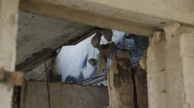 Bombardımandan kaynaklanan şiddetli yıkım, gözle görülür ateş. Mariupol 'de savaştan zarar görmüş bir apartmanın içinde. Kırık beton duvarlar, açık metal demirler. Çatışma sonrasını mahveder. Kapalı savaş çarpışma sahnesi. Yavaşla