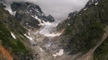 Svaneti dağlarının hava manzarası, Gürcistan 'daki Chalaadi buzulu. Karla kaplı tepeler, kayalık manzaralar, dramatik bulutlar. Engebeli arazi, doğal güzellik, macera turizmi, yürüyüş araştırması. İHA atışı