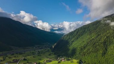 Kafkasya dağlarının Svaneti 'deki hava hipervanesi. Yeşil vadiler, köyler, uzaktaki kar zirveleri. Bulutlar ormanlık tepelerin üzerinde yüzer. Manzara doğa videosu seyahat reklamları veya ekolojik belgeseller için mükemmeldir..