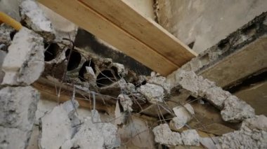 Sallanan ahşap kirişlerle çökmüş tavanlar binanın içinde çatışma yüzünden harap olmuş. Savaştan zarar görmüş apartman dairesi yıkılmış duvarlar, yıkılmış beton, enkaz dolu odada ortaya çıkan demirler gösteriyor..