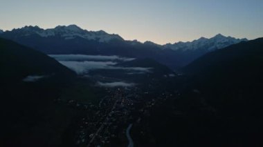 Mestia 'daki Svaneti Dağları Vadisi' nin hava manzarası, gün doğmadan önce alacakaranlıktır. Köyün üzerinde sis, dağınık ışıklar. Karla kaplı tepeler sakin bir manzara. Huzurlu sabah sahnesi. İHA atışı