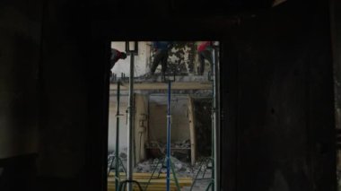 2023-07-30 - Mariupol, Ukrayna. İnsanlar yanmış yapıları yeniden inşa etmek için yıkıyorlar. İnşaat işçileri tavanları söküyor, duvarlar savaştan zarar görmüş apartmanda matkap kullanıyor. Yavaş çekim.