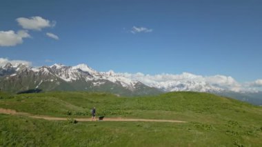 Svaneti Dağları 'ndaki Alp Çayırları' nda yürüyen insan görüntüsü. Solo gezgin, sakin manzarayla çevrili manzaralı bir yolda yürüyor. Depresyon kavramı, yalnızlık, macera keşfi. İHA atışı