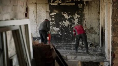 2023-07-30 - Mariupol, Ukrayna. Profesyoneller güvenlik malzemelerinin enkazını temizliyor. İnşaat işçileri duvarları yıkmak için kaya matkabı kullanıyorlar. Yanmış bir apartmanın tavanlarını yeniden inşa etmek için. Yavaş çekim.