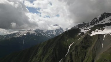 Svaneti 'deki Kafkas dağlarının havadan görünüşü. Karla kaplı tepeler, zengin yeşil vadiler, dramatik bulutlar. Doğa, seyahat, turizm, macera, manzara, çevre, yürüyüş manzarası için idealdir. İHA