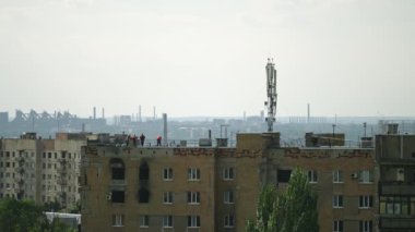 Beton atıkları kaldırma, şehir ortamında yeniden yapılanma. İşçiler savaştan zarar görmüş çatı plakalarını konut binasında vinçle söküyorlar. Mürettebat yıkım ve ihtilaf sonrası kurtarma operasyonları gerçekleştiriyor. Yavaşla