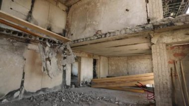 Yanmış duvarlar, çökmüş tavanlar, yerleşim alanındaki döküntüler. Hasarlı dairenin içi savaş sonrasını gösteriyor. Görünür yıkım, sivil inşaata savaş etkisi.