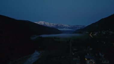 Mestia 'daki Svaneti dağlarının hava manzarası. Gün doğmadan önce alacakaranlık, karlı tepeler, nehir akıntısı, köy evleri, ışıklar, dingin manzara, doğal güzellik, sabahın erken saatleri, kırsal, sakin dramatik.