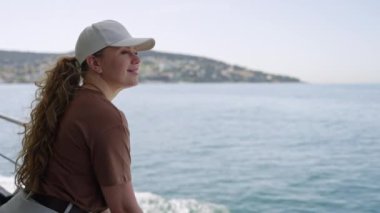 Sakin deniz, güneşli hava, seyahat macerası. Kadın teknede dinleniyor, kıyı manzarasından hoşlanıyor. Dişi turist manzaralı okyanus manzarasını keşfediyor. Boş zaman, özgürlük, deniz kenarı gezisi.