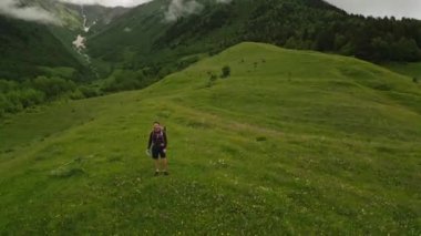 Sırt çantalı gezgin, Svaneti dağlarındaki dağlık arazinin manzarasını seviyor. Yürüyüşçülerin araziyi keşfetmesi. Güzel dağ manzarası. Macera, seyahat, özgürlük, doğa keşfi. İHA atışı
