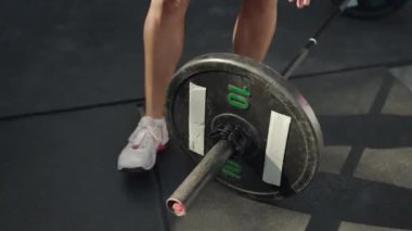 Eller bileklikte, ağırlık plakası kaldırma seansı için güvenli. Yakın plan, sporcu güneş ışığı altındaki kaldırım spor salonunda Olimpik halterden klempi çıkarıyor. Fitness rutini sona erdi, ekipmanlar yerleştirildi. Yavaş çekim.