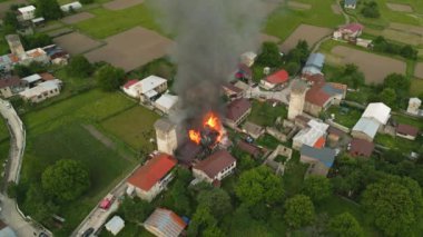 Mestia köyündeki Svan Kulesi 'nde yangın söndüren itfaiye ekibi, itfaiye aracı görüntüsü. İtfaiyeciler alevlerle savaşır, duman yükselir. Kırsal Gürcistan manzarası acil durum tepkisi. İHA atışı