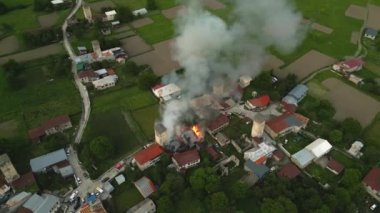 Mestia 'daki Svan kulesi yangınının hava görüntüsü. Ortaçağ kuleleri ve evleri olan yeşil vadide duman ve alevler. Acil durum, felaket kurtarma operasyonları. İHA atışı