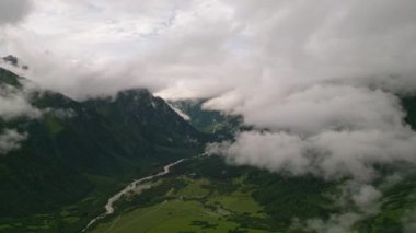 Mazeri köyü, Svaneti dağları üzerindeki bulutlar. Yeşil vadiler, kıvrılan nehir, görünen dağ zirveleri. Manzaralı, huzurlu bir ortam. Panoramik dron görüntüsü. Doğa, manzara turizmi.