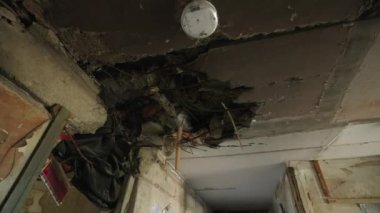 Hasar, yerleşim yerindeki kırık kablolar ve molozlar ortaya çıktı. Video, Mariupol 'ün dairesindeki mermi kovanının tavanında delik olduğunu gösteriyor. Ukrayna şehrindeki yıkım çatışmalar sırasında kaydedildi. Yavaş çekim.