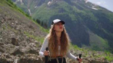 Sırt çantalı kadın yürüyüşçü Svaneti dağlarının manzarasının tadını çıkarmak için duruyor. Etrafına bakıyor, çarpıcı manzaraya dalmış. Karla kaplı tepeler, yeşil vadiler arka plan oluşturur. Açık hava macera doğa keşfi.