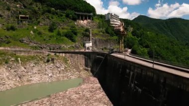 Svaneti Georgia 'daki Inguri hidroelektrik santralinin hava görüntüsü. Ağaç reçelli dağ barajı ve suda yüzen odun enkazı. Su istasyonunu çevreleyen yeşil dağ manzarası. İHA atışı