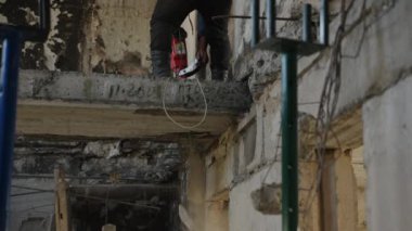 Yanmış tavanları temizleyen bir adam, konut binasındaki duvarları. İnşaat işçisi savaştan zarar görmüş daireyi matkapla yıktı. Yeniden yapılanma, tamir sahnesi gösterildi. Hasarlı beton sahada çalışan.