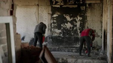 2023-07-30 - Mariupol, Ukrayna. İnşaat işçileri hasarlı duvarları yıkmak için matkap kullanıyorlar savaştan zarar görmüş apartman dairesinde tadilat için. Yavaş çekim.