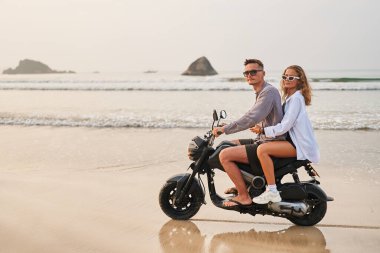 Okyanus kıyısında bir çift scooter sürüyor. Erkek, güneş gözlüklü bir kadını arkada bırakır. Gün batımında motosikletle plajı keşfederler. Bütçe seyahati macerası.