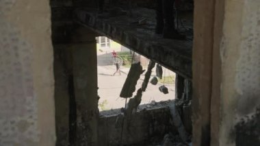 İşçiler bükülmüş metali ağır çekimde söker. Videoda savaş sonrası, Mariupol 'de hasar görmüş zeminleri ve yangından yanmış betonu olan bir bina var. Yavaş çekim.