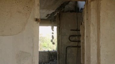 Yıkılan beton duvarlar, boşaltılmış bina iskeletleri ve yıkım sahneleri arasında paslı borular görülebilir. Mariupol 'de savaştan zarar görmüş bir apartman dairesi yangından ve bombardımandan zarar görmüş. Yavaş çekim.
