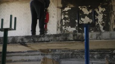 Güvenlik ekipmanları, yoğun enkaz kaldırma, konut binasında yeniden yapılanma çalışmaları. İnşaat işçisi savaştan zarar görmüş apartmandaki betonu delmek için matkap kullanıyor. Yavaş çekim.