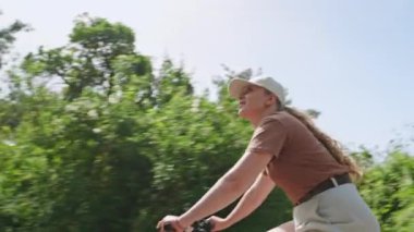 Kozalaklı ormanlarda bisikletçi. Ormanda bisiklet süren bir kadın. Dişi bisikletçi patikada açık hava aktivitelerini sever. Manzaralı yeşil yolda macera. Aktif yaşam tarzı, bisiklet üzerinde doğa macerası.