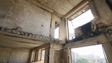 Çökmüş tavanlar, açıkta kalmış kirişler kasvetli bir zemin oluşturuyor. Savaşın parçaladığı apartman dairesi ciddi hasarlar ve yanmış duvarlar gösteriyor. Kentsel bozulma, çatışma sonrası sahne, ıssızlık konut binasında yakalandı..