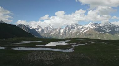 Svaneti dağlarındaki Koruldi göllerindeki yürüyüşçülerin hava manzarası çatısı çadırlı off-road SUV karavanı. Yalnız gezgin doğayı keşfeder, manzarada sırt çantasıyla gezer. Uzak bir yerde macera.