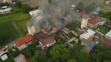 Mestia 'daki Svan Kulesi' nde yangın söndüren itfaiye ekibinin hava görüntüsü. İtfaiyeciler Gürcistan 'daki tarihi binada alevlerle su hortumlarıyla savaşıyorlar. Yanan binadan çıkan duman alevleri.